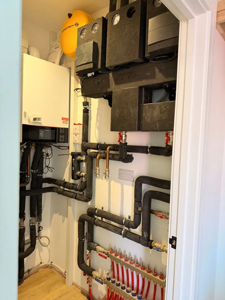 Boiler, hot water cylinder and underfloor heating manifold neatly installed in a plant cupboard