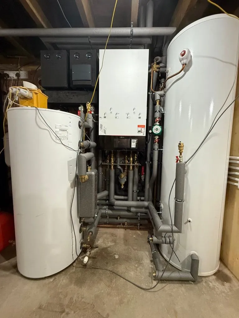 Two hot water cylinders, boiler and heating manifold installed in a loft plant room