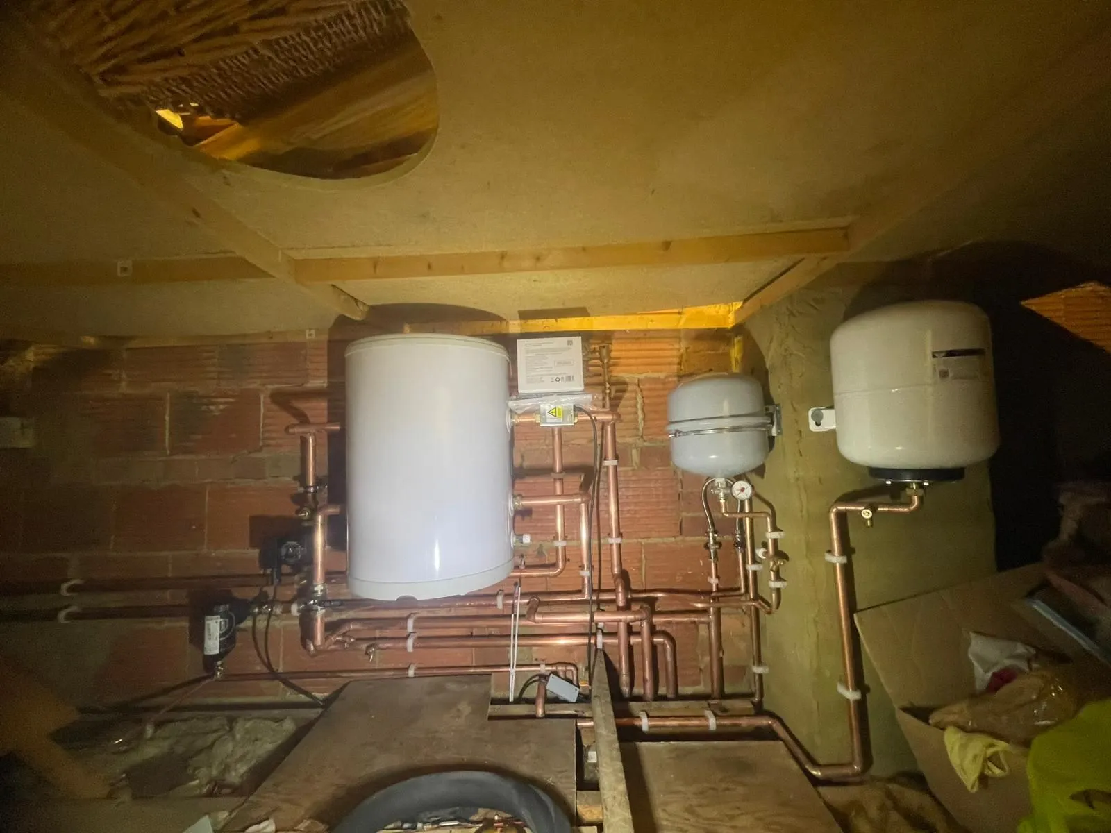 Vented hot water cylinder with expansion vessels and copper pipework installed in a loft